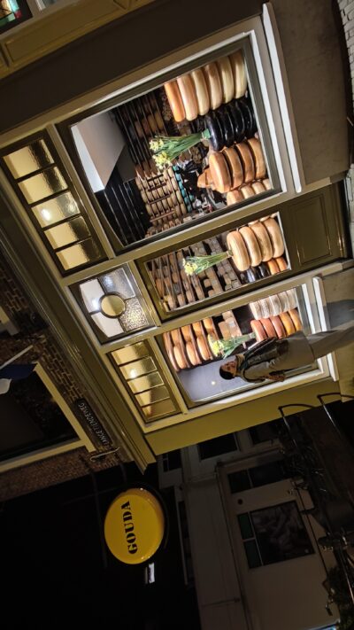 Tienda de quesos Gouda — vitrina iluminada con cartel circular 'GOUDA'